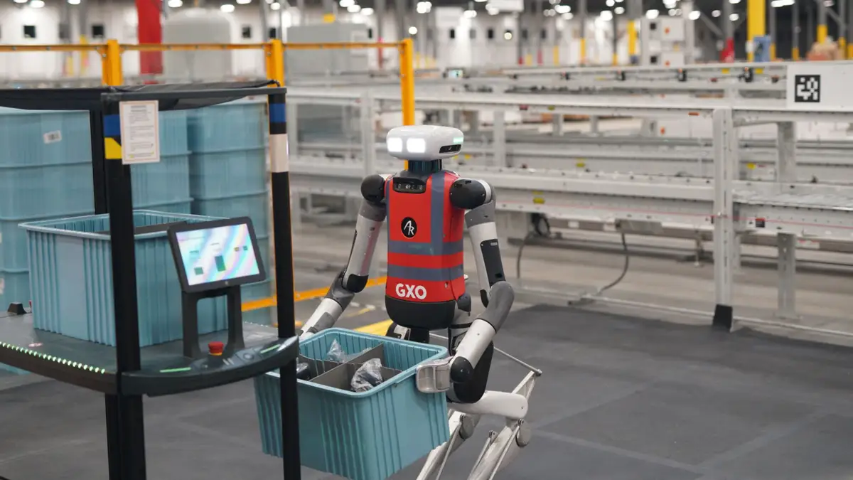Digit humanoid robot moving totes in a warehouse aisle