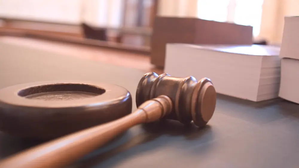 A judge’s gavel resting beside its sound block in a courtroom
