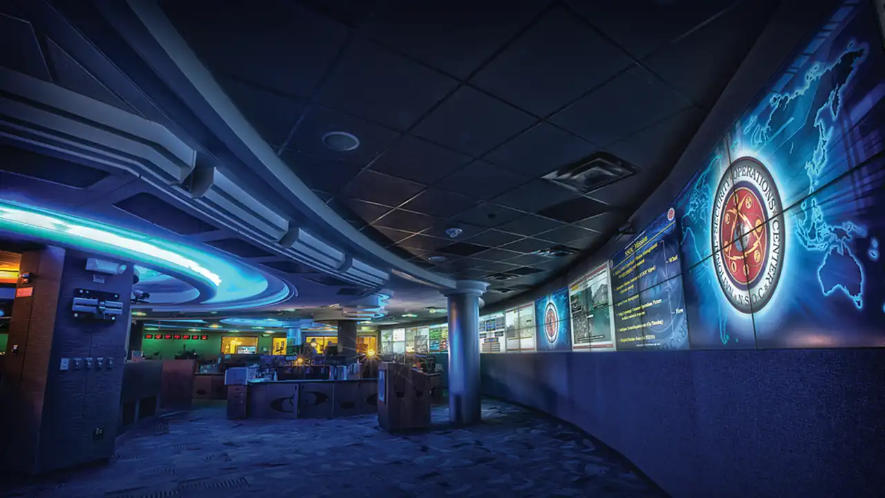 A security operations center with analysts' desks and a wall of monitoring screens