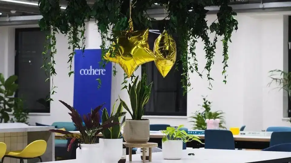 Close view of Cohere office branding with hanging plants and a cohere banner.