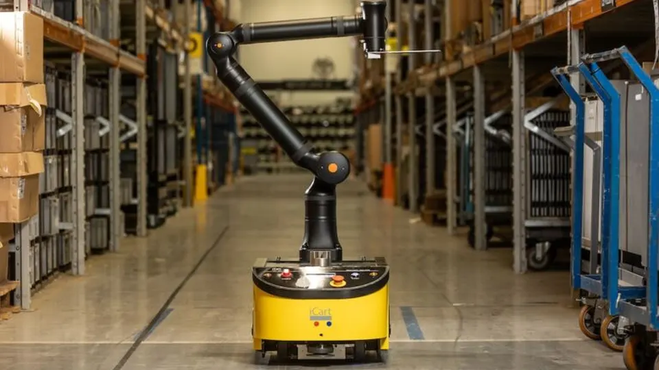 A warehouse robot standing in an aisle between stocked shelves