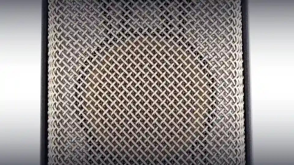 Extreme close-up of the woven metal grille of a studio condenser microphone