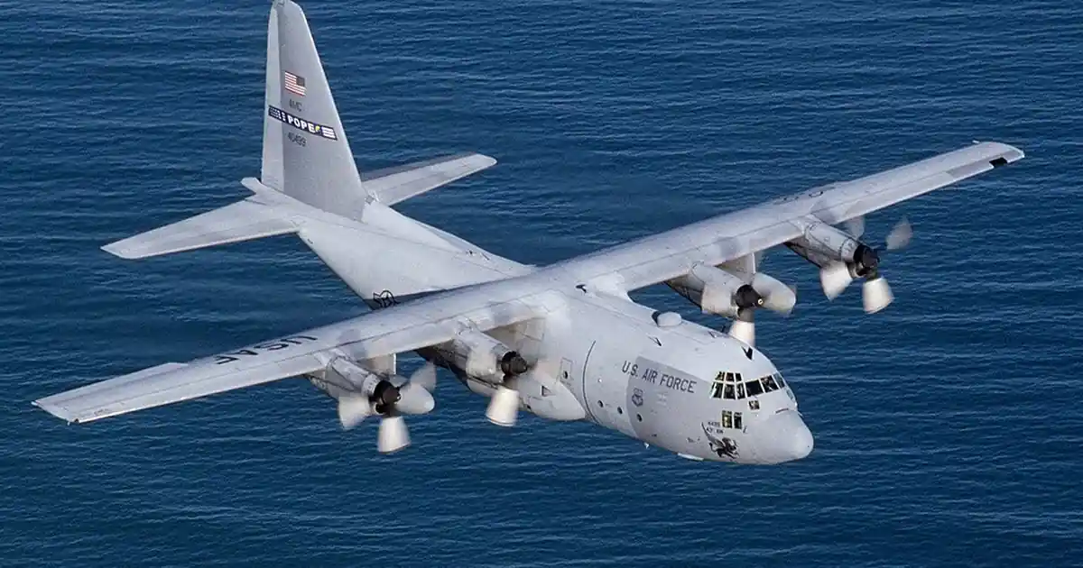 A C-130 Hercules transport aircraft in flight over the ocean