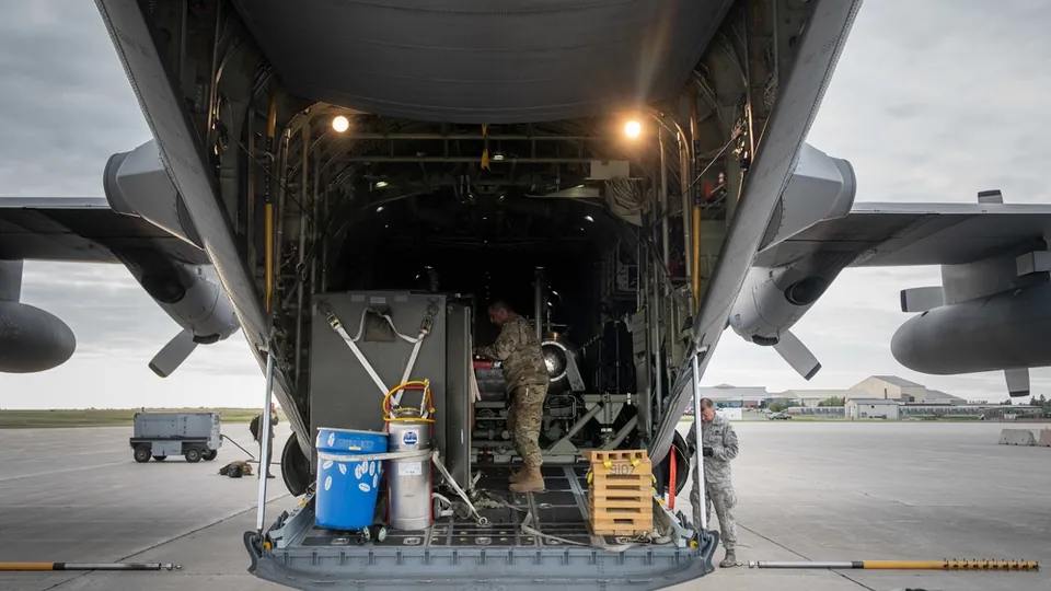 Personnel working at the open cargo ramp of a military transport aircraft on the flight line