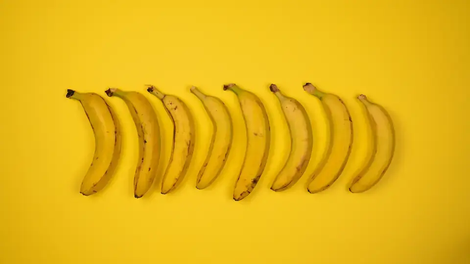A bunch of ripe yellow bananas photographed against a white background.