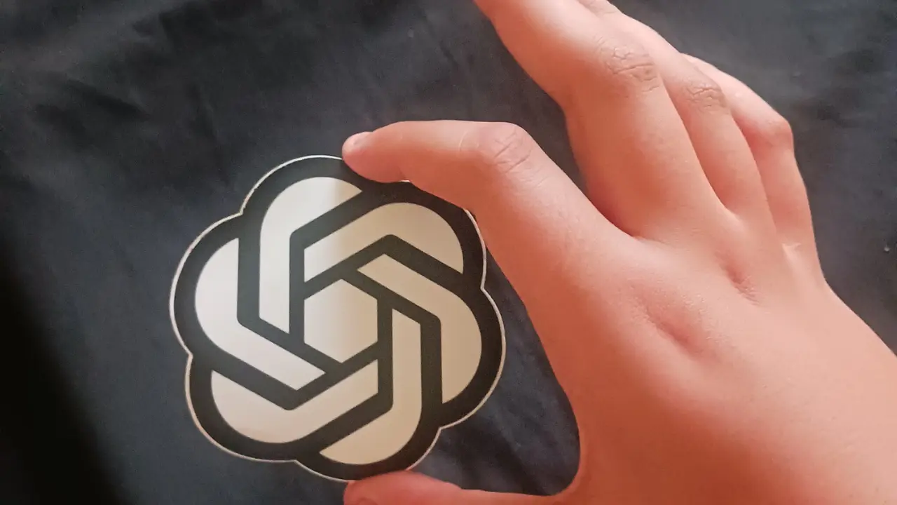 A hand holding the OpenAI logo.