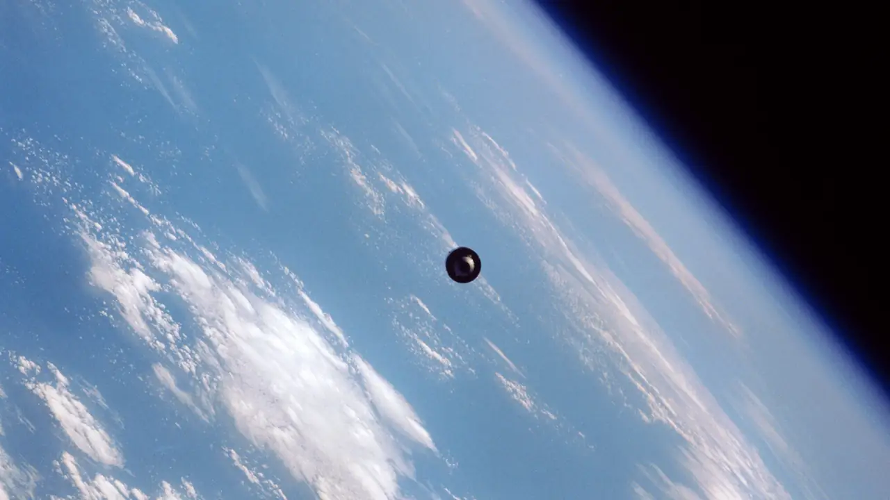 The SBS-4 communications satellite silhouetted above Earth's limb and cloud cover