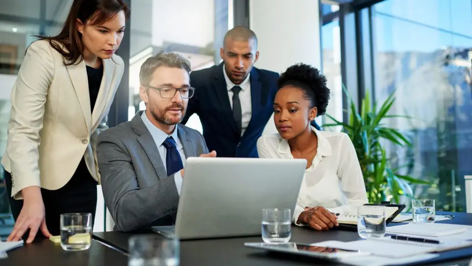 Business colleagues collaborating around a laptop in a modern office