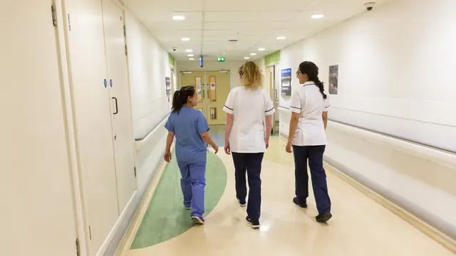 NHS staff walking through a hospital corridor.