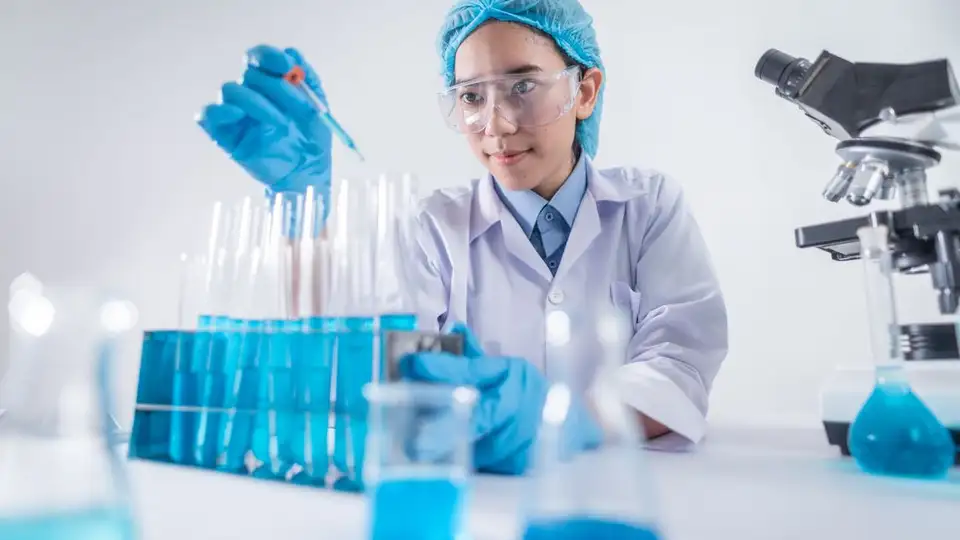 A researcher pipetting samples next to a microscope in a laboratory