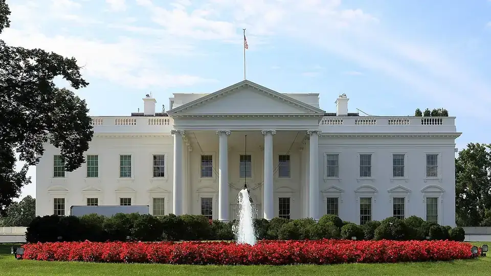 The White House north facade with its columned portico, fountain, and flag