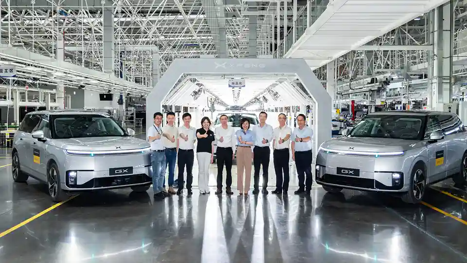 XPeng staff with two GX robotaxis at the factory.