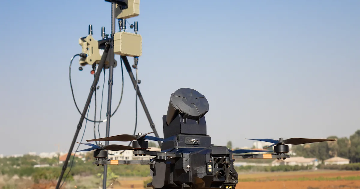 An XTEND drone with a net-launcher payload beside ground sensor equipment in the field.
