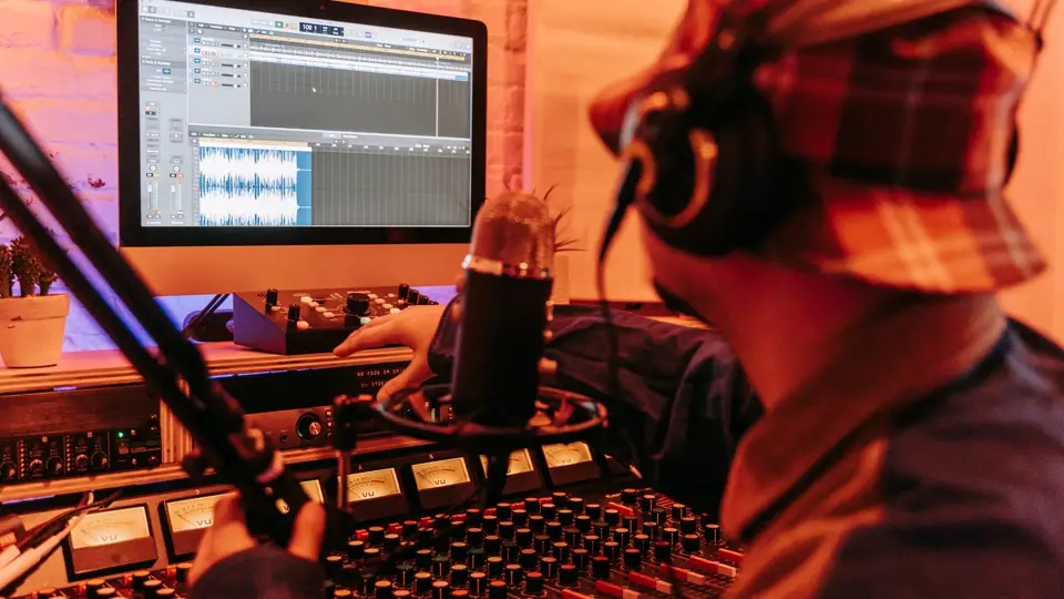 Music producer working at a computer with mixing equipment in a dark studio